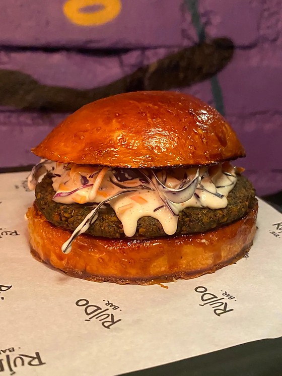 Burguer de falafel no pão brioche com coleslaw, sobre o papel timbrado do Ruído.